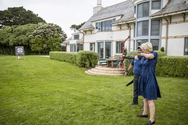 Senior woman taking a private archery class at Wharekauhau Lodge in Wairarapa, New Zealand.