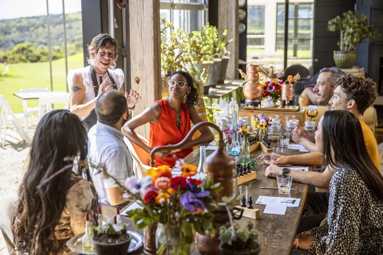 Group of people seated around a table at a private wine tasting in Waiheke, Auckland, New Zealand, listening to a host explain the winemaking process and sampling local wines.