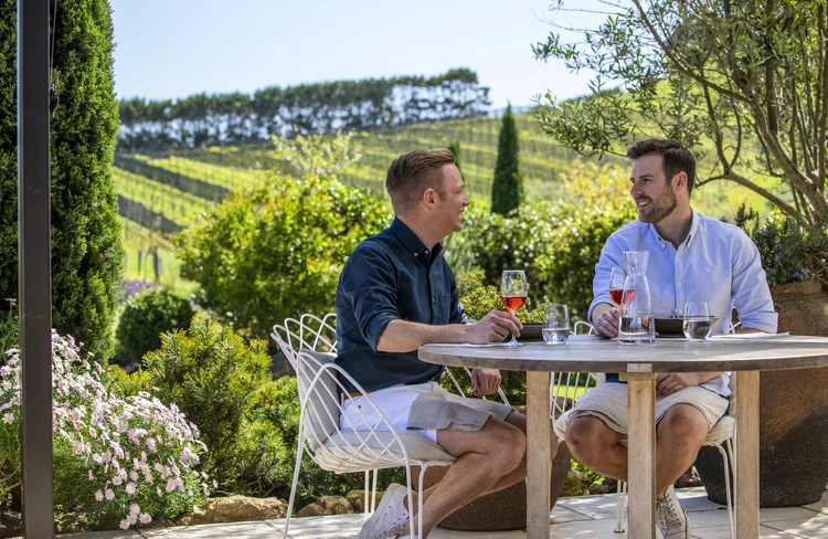 Two men sitting and enjoying a glass of wine together at a vineyard in New Zealand.