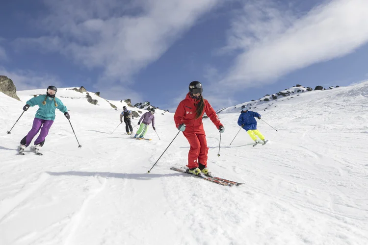 Group of people skiing down the Southern Alps in Queenstown, New Zealand.