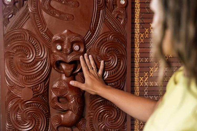 Woman touching traditional Maori art in Rotorua, Bay of Plenty, New Zealand.