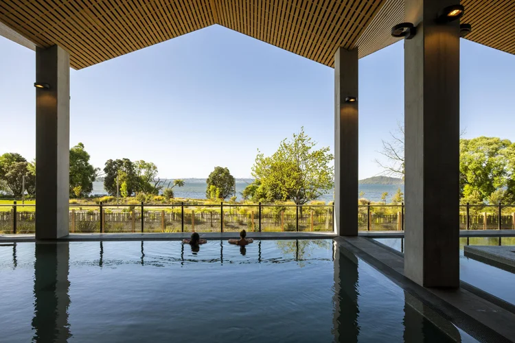 Two people relaxing in an indoor pool at the Wai Ariki Hot Springs & Spa in Rotorua Bay, New Zealand.