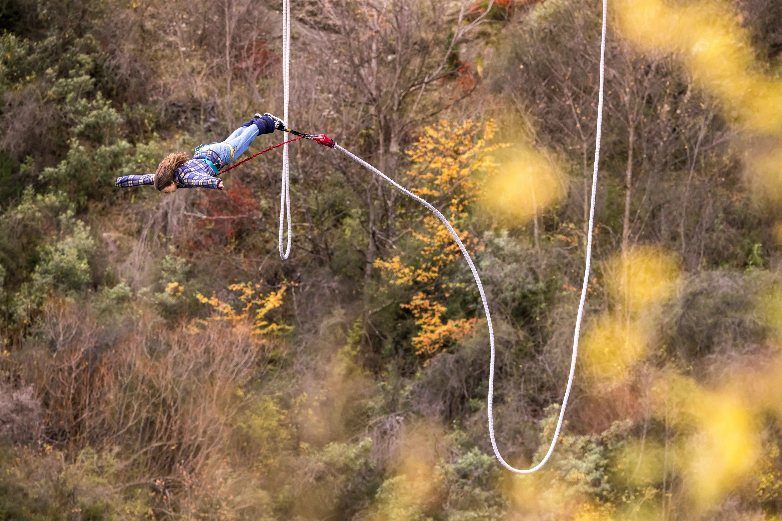 A person leaps from the Kawarau Bridge during a bungee jump, suspended above the turquoise river below in Queenstown, New Zealand