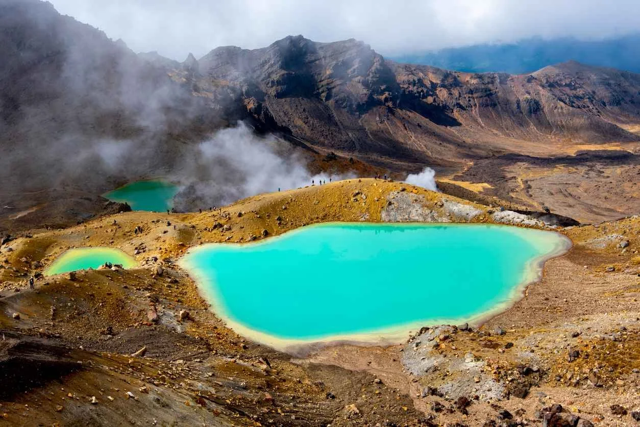 A scenic view of the Tongariro Alpine Crossing’s famous Emerald Lakes, glowing bright green against the rugged volcanic landscape
