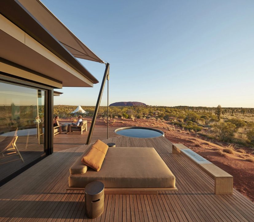 View of an outdoor bed, seating, and a private pool with a view of Ayers Rock at the luxury resort, Longitude 131, in Uluru, Australia.