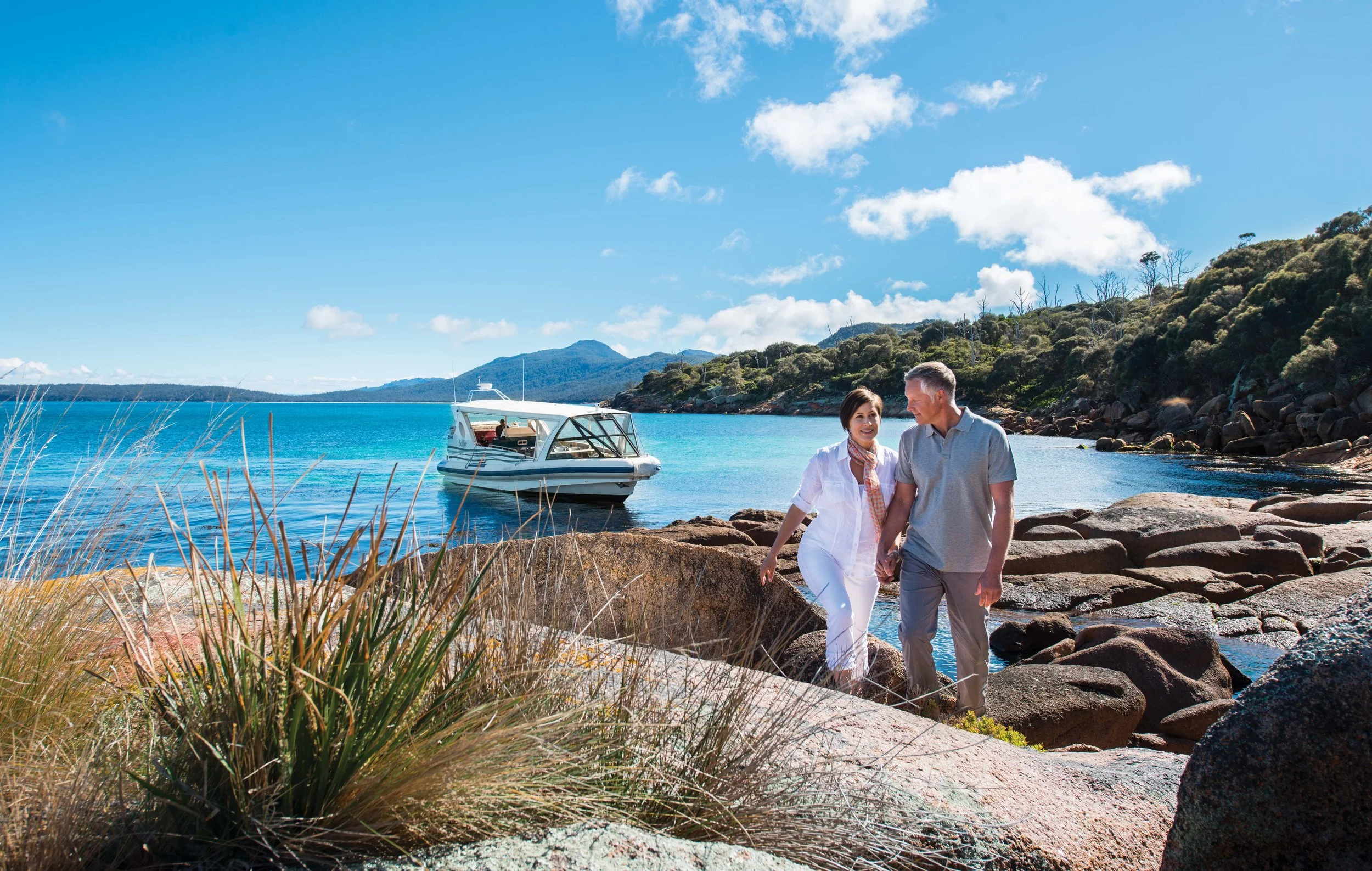 A senior couple walking near a luxury boat in Freycinet, Australia.