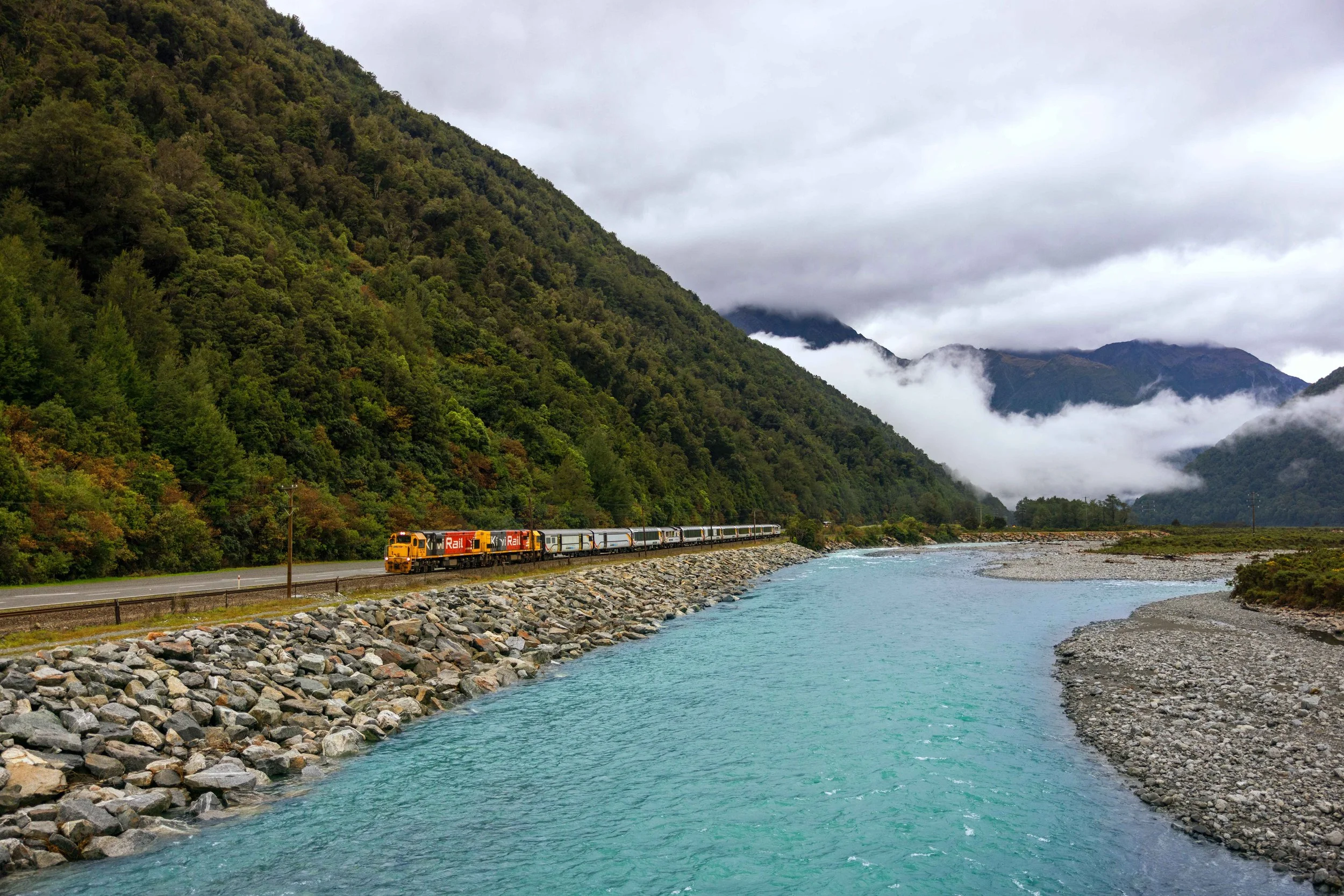 The TranzAlpine Railway winds through the lush green mountainsides and blue rivers of Christchurch on its scenic journey across New Zealand