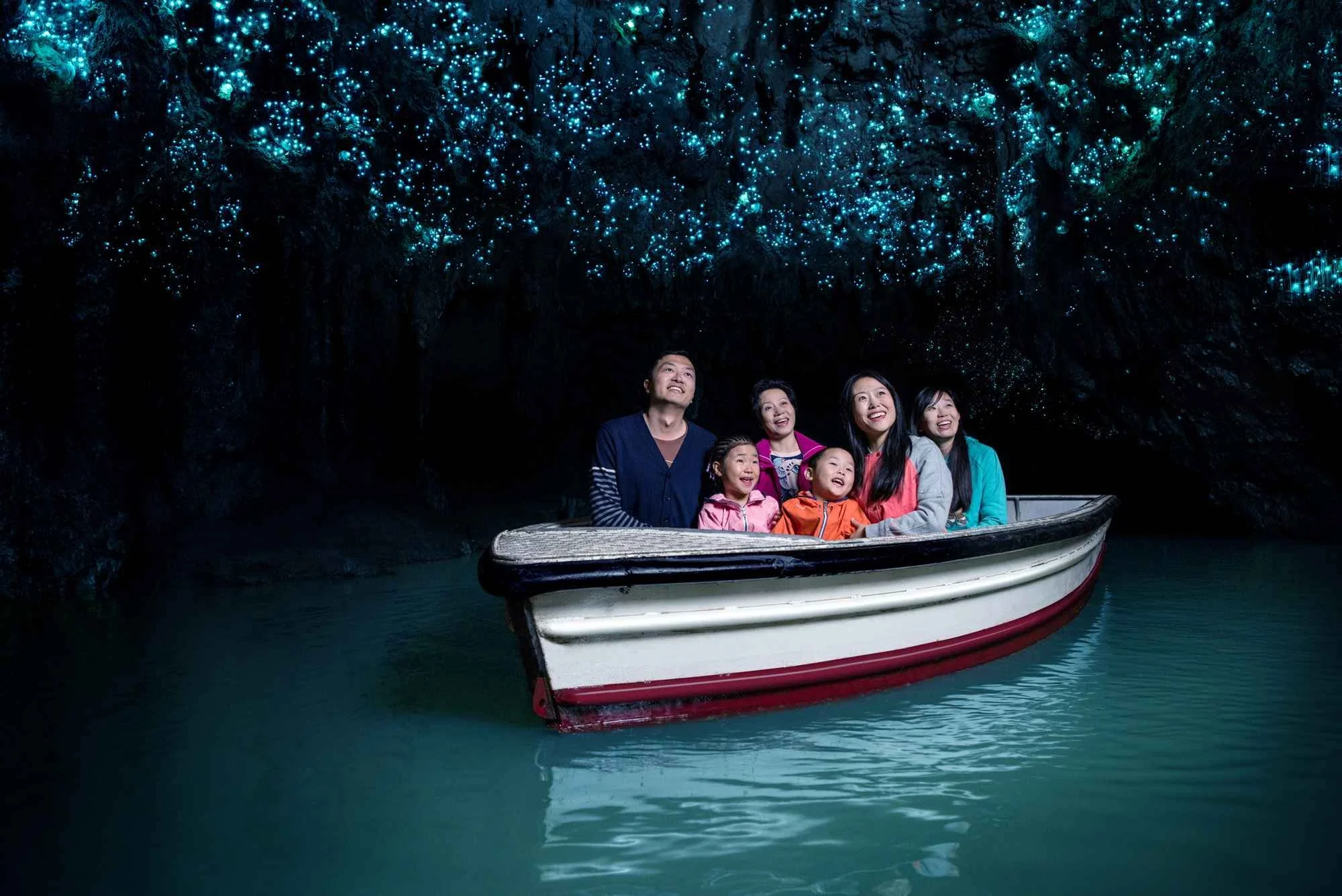 Visitors explore the Waitomo Glowworm Caves, drifting beneath thousands of tiny blue bioluminescent glowworms illuminating the dark limestone chambers