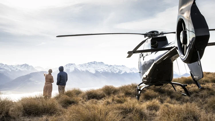A couple looking at a scenic viewpoint they reached by a private helicopter ride in New Zealand.