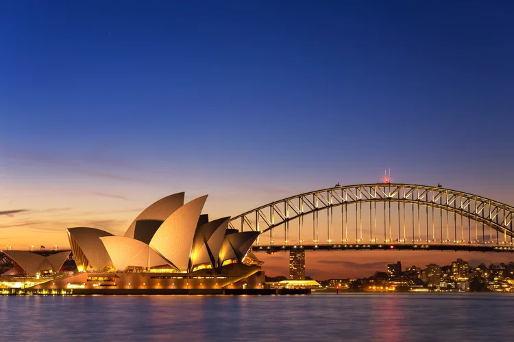 Beautiful Opera house view at twilight time with vivid sky and illumination on the bridge in Sydney, New South Wales, Australia.