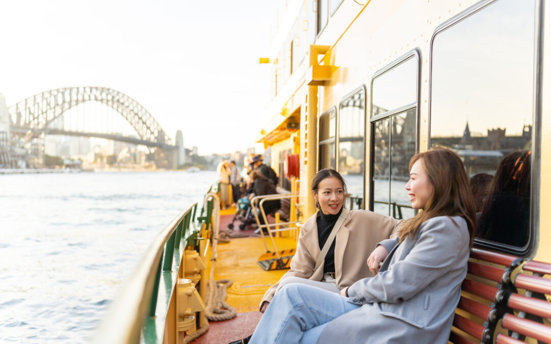 Two women travel Sydney Harbour in Australia on ferry boat on holiday vacation.