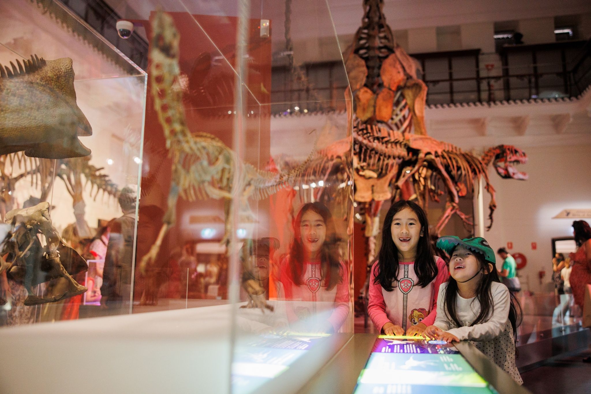 Two young girls enjoy family-friendly museum in Sydney. The display features dinosaur bones.