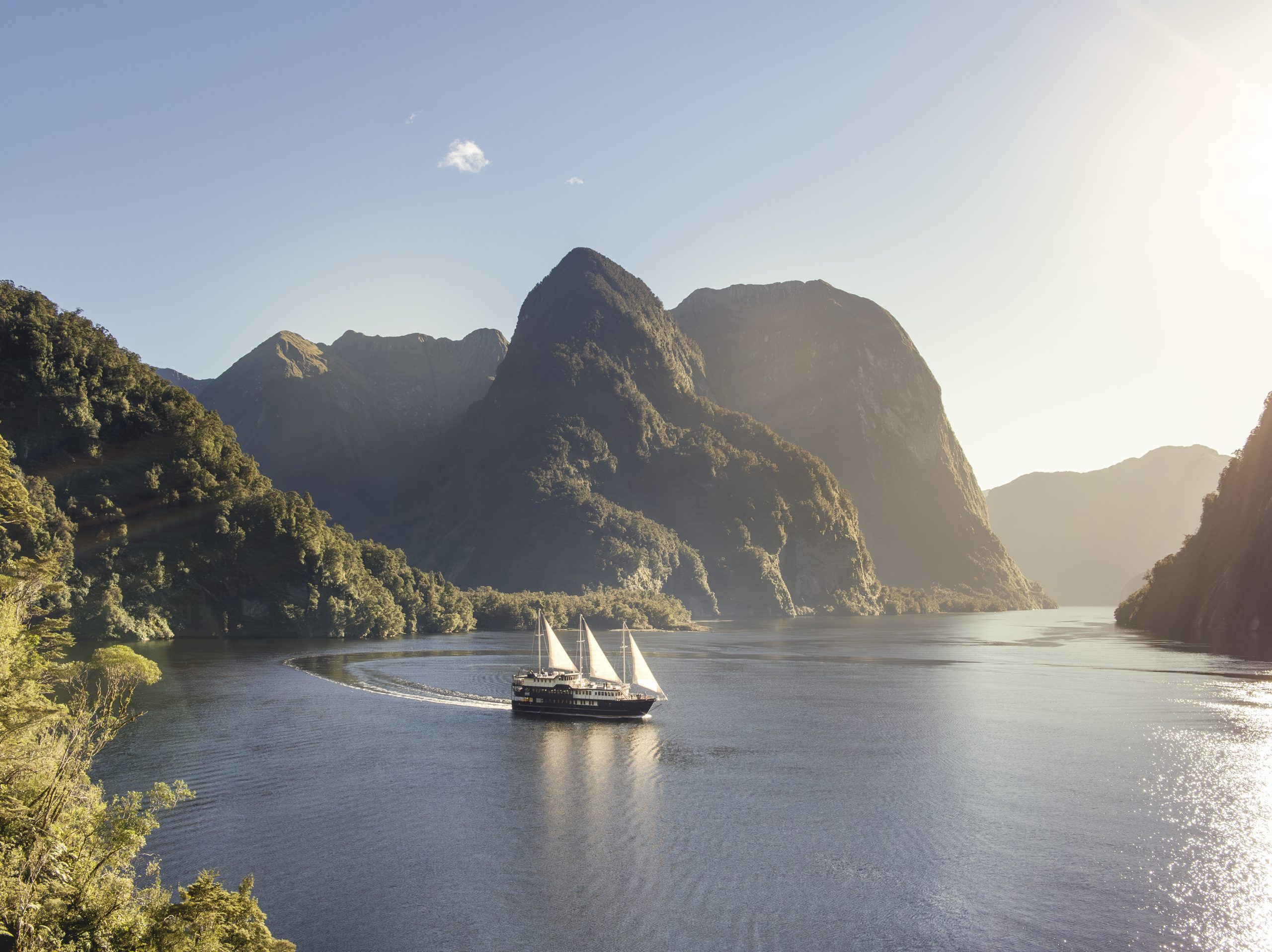 A small boat cruises through Doubtful Sound, “Patea”, fiord in Fiordland, NZ.