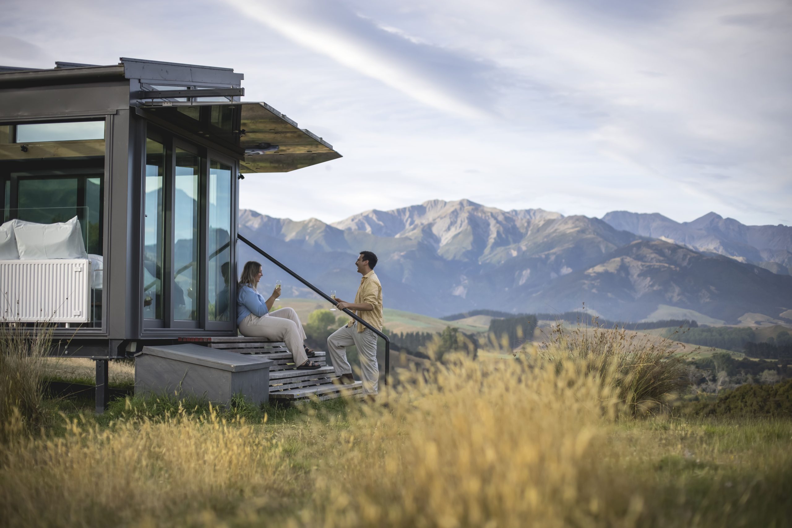 Couple enjoying a glass of wine together outside their luxury accomodation at Pure Pods in Canterbury, NZ
